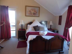 a bedroom with a large bed with red curtains at Avondsrus Guesthouse in Bettyʼs Bay