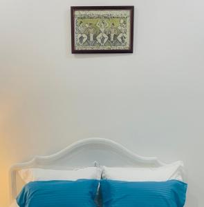 a bed with two blue pillows and a picture on the wall at Villa Tranquility in Ja-Ela