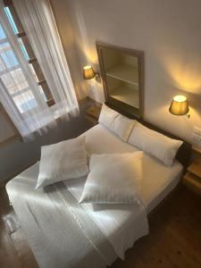 a bedroom with a white bed with pillows and a mirror at Castellorizon Pensione in Meyisti