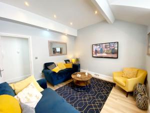 a living room with a blue couch and yellow chairs at Sovereign House Luxury Apartment in Torquay