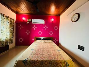 um quarto com uma cama com uma parede vermelha em Anant Beach Villa em Ratnagiri