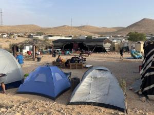 un grupo de tiendas en el desierto con gente sentada alrededor en חאן נחל חווה Han Nahal Hava en Mitzpe Ramon