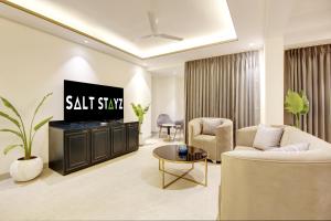 Saltstayz Amara - Near MG Road and Sector 29 في جورجاون: غرفة معيشة مع تلفزيون وأريكة وطاولة
