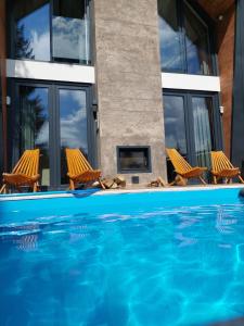 a swimming pool with two chairs and a fireplace at Orange Villa with private pool in Ilidža