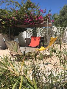 um grupo de cadeiras e um guarda-sol na areia em Suite indépendante Chez l'Artiste em Midoun