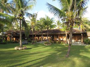 a resort with palm trees in front of a yard at Villa Sedeoen in Nembrala