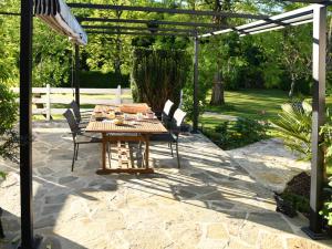 d'une terrasse avec une table et des chaises en bois sous une pergola. dans l'établissement l'Orée du Bois, à Saint-Brice