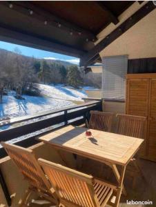 una mesa de madera y sillas en un balcón con vistas en Trés jolie duplex à Ancelle, en Ancelle