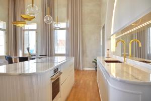 a large kitchen with white cabinets and gold faucets at La Torre Residenza Imperiale in Chania