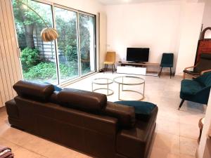 a living room with a brown leather couch and a tv at Bamboo villa in Meudon
