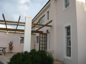 a white house with a wooden pergola at Avondsrus Guesthouse in Bettyʼs Bay