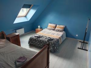 1 dormitorio azul con 2 camas y ventana en Le palmier nantais, en Mouzeil