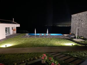 a yard with chairs and a pool at night at João de Oliveira - casas de campo in Santo António