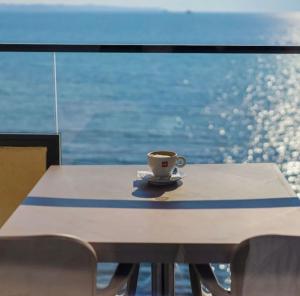 une tasse de café assise sur une table devant une fenêtre dans l'établissement Amara Hotel & SPA, à Durrës