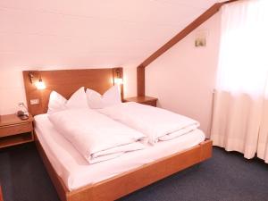 una camera da letto con un grande letto con cuscini bianchi di Hotel Schuster a Colle Isarco