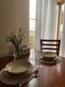 uma mesa com pratos e copos e um vaso com flores em Willa Polanka em Gościno
