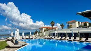 a swimming pool with lounge chairs and umbrellas at Liberatos Village in Lassi