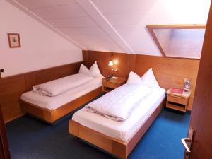 two beds in a small room with two tables at Hotel Schuster in Colle Isarco