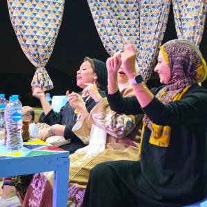 Eine Gruppe Frauen, die mit erhobenen Händen am Tisch sitzen in der Unterkunft Opal privat nubian hotel in Assuan