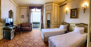 een hotelkamer met 2 bedden en een televisie bij Windsor Palace Luxury Heritage Hotel Since 1906 by Paradise Inn Group in Alexandrië
