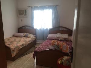 two beds in a small room with a window at شاليه بقرية هوليداى فانتازيا راس سدر in Raʼs Matarma +15 photos
