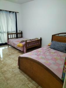 a bedroom with two beds and a tiled floor at شاليه بقرية هوليداى فانتازيا راس سدر in Raʼs Matarma