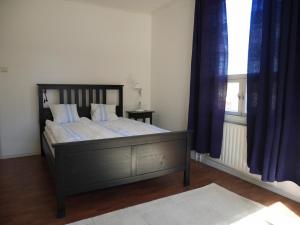 Schlafzimmer mit einem Bett mit blauen Vorhängen und einem Fenster in der Unterkunft Lindallén Guest House in Fiskars