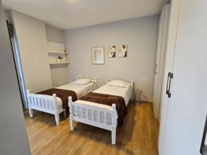 twee bedden in een kleine kamer met houten vloeren bij SKY DWELLING TIRANA in Tirana