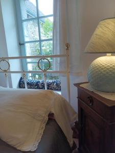 ein Schlafzimmer mit einem Bett mit einer Lampe und einem Fenster in der Unterkunft Art Cottage in Pontlevoy