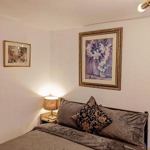 a bedroom with a bed and a painting on the wall at Small apartment in the heart of Selsdon! in Addington