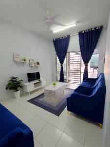 sala de estar con 2 sofás azules y TV en FIRASH HOMESTAY AT SERI ISKANDAR en Seri Iskandar