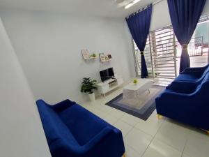 sala de estar con 2 sillas azules y TV en FIRASH HOMESTAY AT SERI ISKANDAR en Seri Iskandar