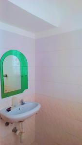 a bathroom with a white sink and a green mirror at Marion's incredible 1 bedroom apartment in Watamu +2 photos