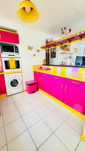 a kitchen with pink and yellow cabinets and a washing machine at La vie en rose: piscine et vue mer in Le Gosier +41 photos
