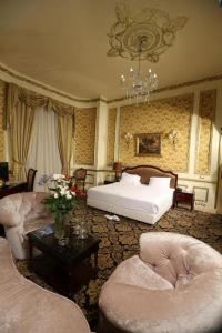 a bedroom with a bed and two chairs and a table at Windsor Palace Luxury Heritage Hotel Since 1906 by Paradise Inn Group in Alexandria