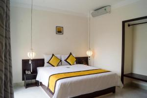 ein Schlafzimmer mit einem großen Bett mit gelben Kissen in der Unterkunft Phuc Thao Villa in Hoi An
