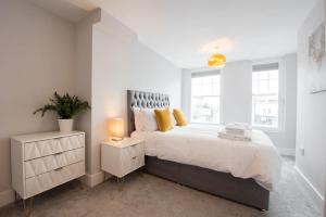 een witte slaapkamer met een groot bed met gele kussens bij Modern,Bright and spacious 2 bed in Brentwood