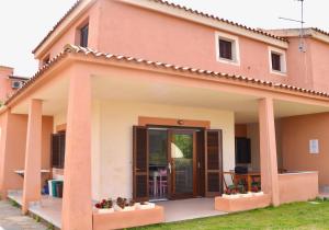 ein rosa Haus mit einer großen Tür davor in der Unterkunft ISS Travel, Gli Asfodeli - Large apartments with private terrace in San Teodoro