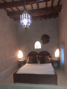 1 dormitorio con cama y lámpara de araña en Dar Amazir en Agdz