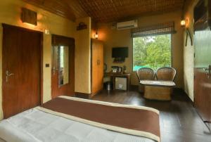 Marchula的住宿－Tashree Kabeela Riverside Resort，一间卧室配有一张床、两把椅子和一个窗户