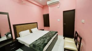 Schlafzimmer mit einem Bett, einem Spiegel und rosafarbenen Wänden in der Unterkunft BLD Restaurant And Home Stay in Dehradun