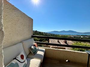 a couch on a balcony with a view of the ocean at Studio Vue Mer - Piscine - Porticcio in Porticcio
