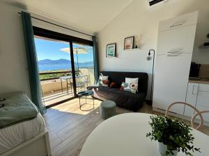 uma sala de estar com um sofá e uma janela com vista em Studio Vue Mer - Piscine - Porticcio em Porticcio