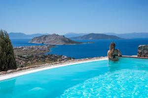 AegenitissaSunkissed Villa的坐在游泳池里看着大海的女人