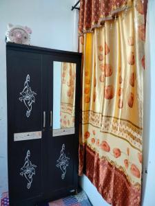 KomodoにあるAtta Ratu Homestayのカーテン付きの部屋の黒いキャビネット