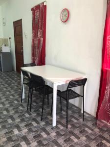 a white table with chairs and a clock on a wall at Homestay Idaman B B with 2 room aircond 2 Quen Bed and Not Sharing Room -Privacy in Kuala Terengganu
