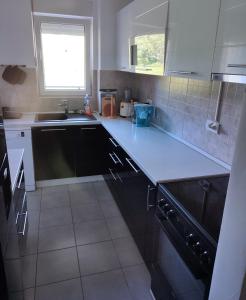 a kitchen with white cabinets and a sink at A l e k a in Radovići
