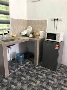 a small kitchen with a microwave and a refrigerator at Homestay Idaman Bukit Berapit dengan 2 Bilik Tidur AirCond-Harga utk 1 rumah in Kuala Terengganu