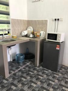 a small kitchen with a microwave and a refrigerator at Homestay Idaman B B with 2 room aircond 2 Quen Bed and Not Sharing Room -Privacy in Kuala Terengganu