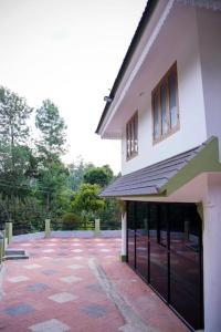 a large white building with a red brick patio at New Heaven Group accommodation in Thekkady